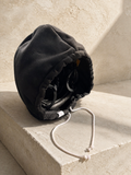 Black Bucket Hood covering a hockey helmet and visor, angled on a warm limestone block